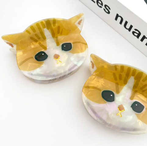A stylish and quirky cat face hair clip designed for cat lovers, shown in a clean, glossy white finish.