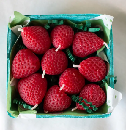 Display a colorful harvest of strawberry candles neatly arranged in a green-lined basket from Happy Organics.