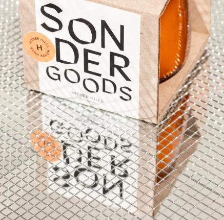 A minimalist Sonder Goods soy candle in an amber glass jar, featuring a destination-inspired scent like Hither Hills.