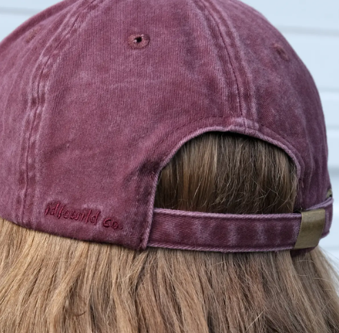 The back of the washed burgundy baseball cap showcasing the adjustable strap, metal buckle closure, and subtle brand embroidery.