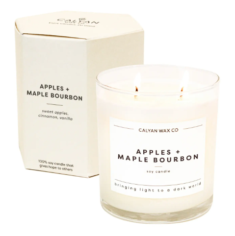 Calyan Wax Co.'s Apples + Maple Bourbon Candle in a clear glass tumbler with a cream hexagon box, delivering a sweet autumn aroma.