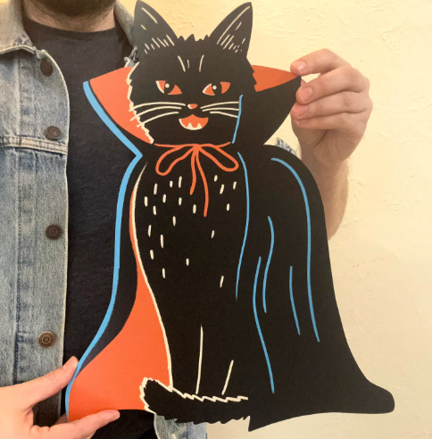 Bring spooky elegance to any room with the Vampire Cat cutout wall decoration by Zander Mack, highlighting its detailed cape design.