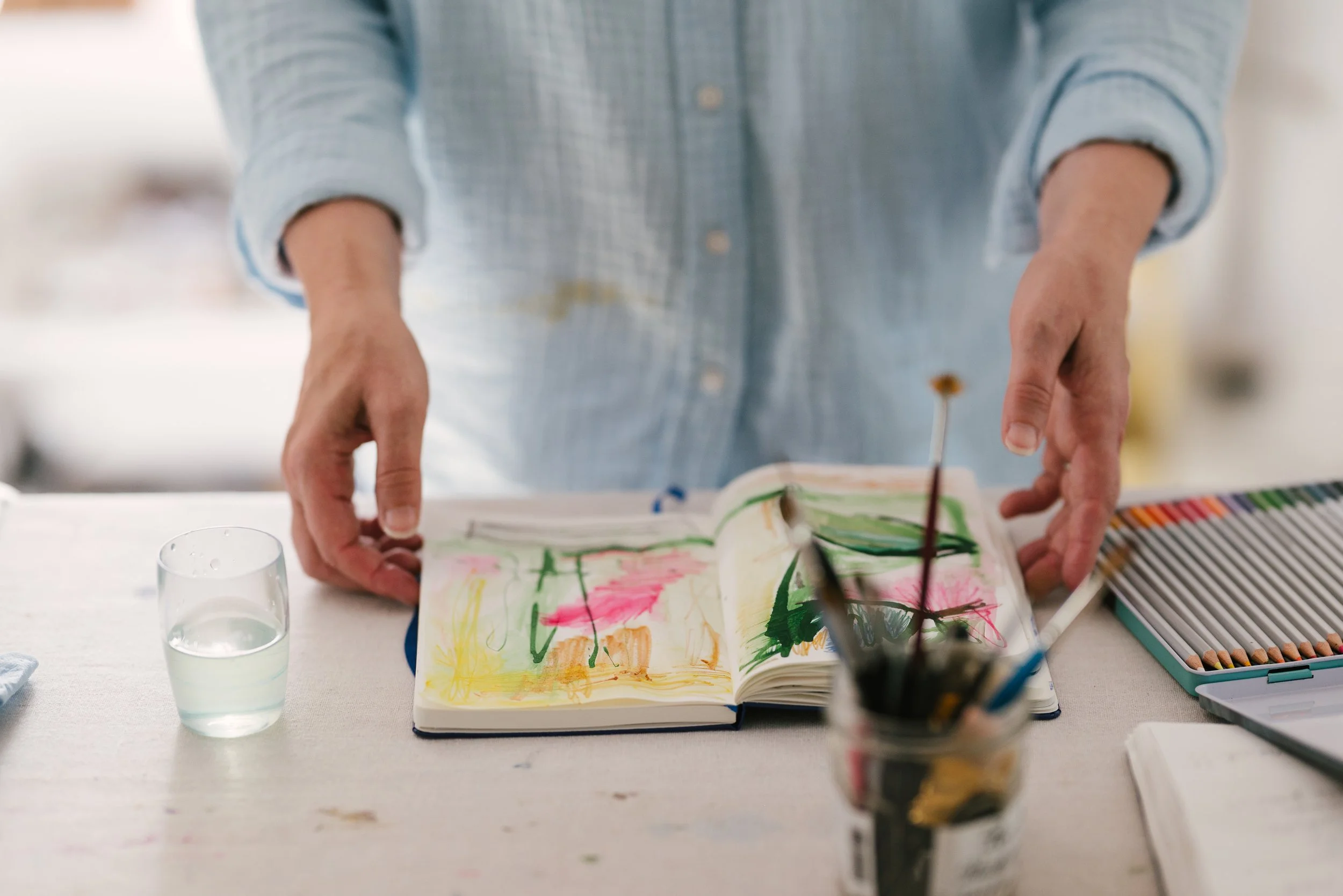 A 3/4 view of female artist hands holding a sketchbook, photographed by Chester County artist Tina Crespo
