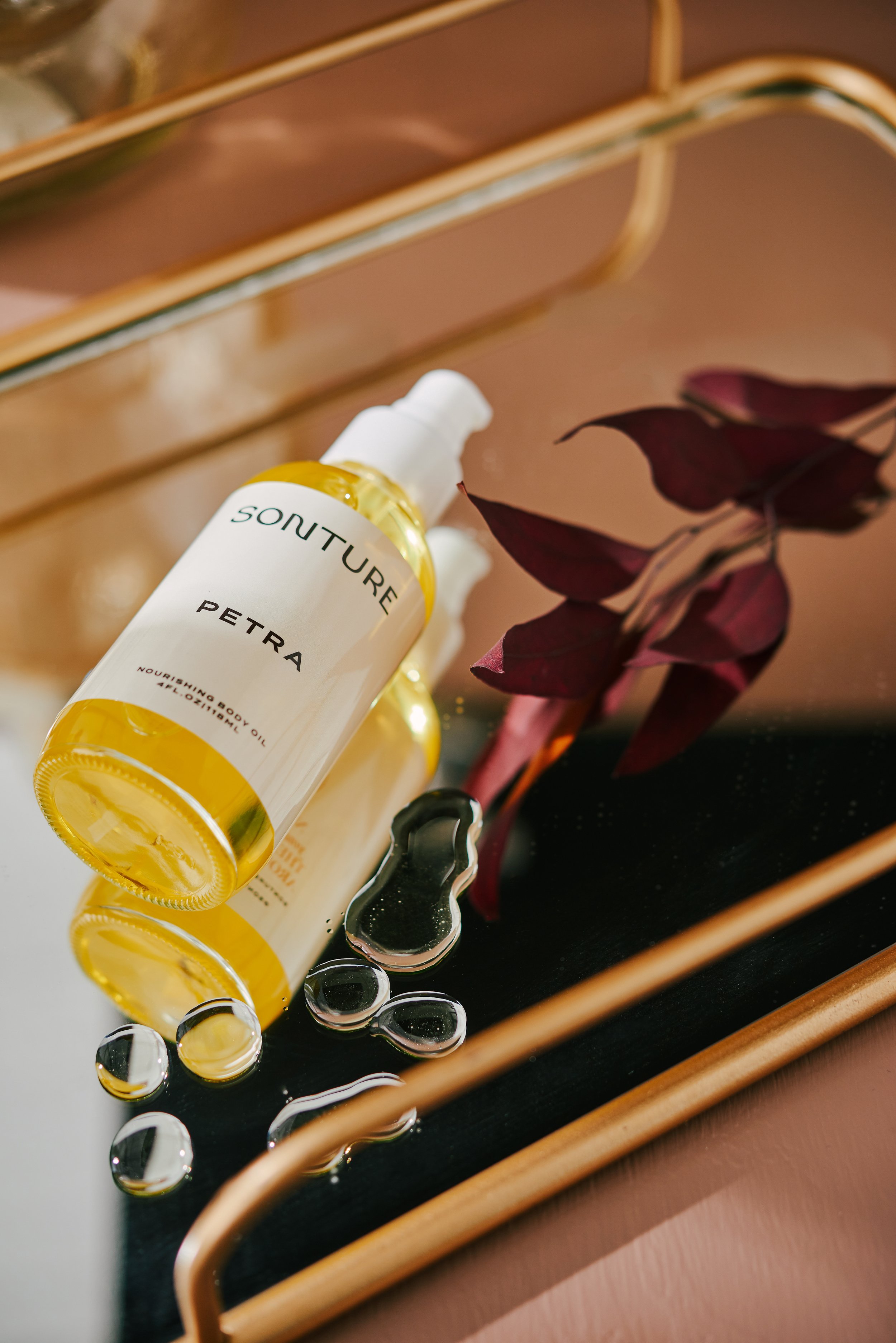 Sonture Beauty bath and body products photographed by Philadelphia photographer Tina Crespo, showcasing body oil on mirror tray with drops of body oil.