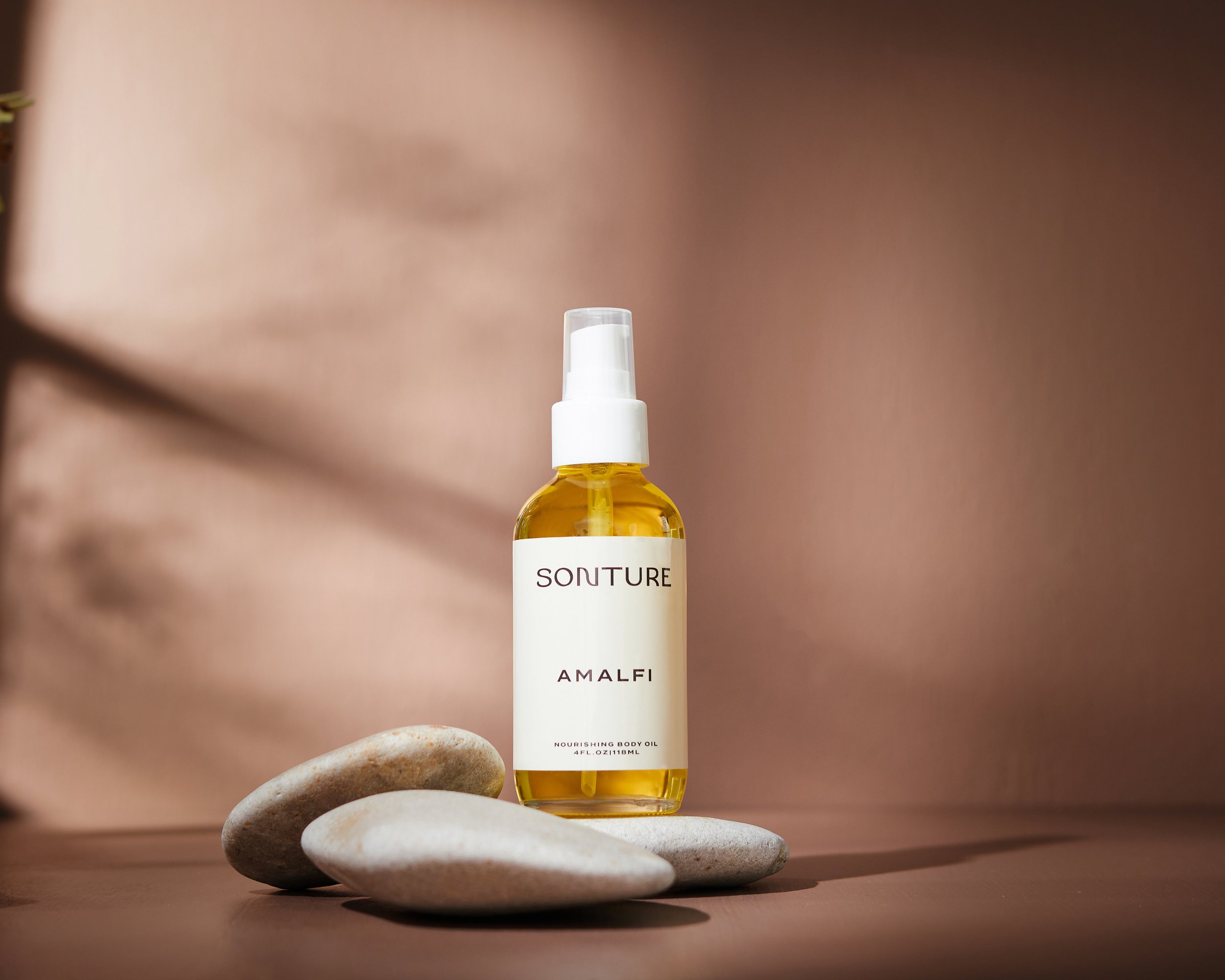 Sonture Beauty bath and body products photographed by Philadelphia photographer Tina Crespo, showcasing body oil on simple warm brown background.