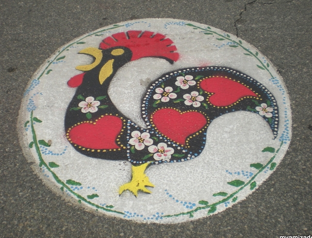 PORTUGUESE PRIDE The colorful Galo de Barcelos , Rooster of Barcelos, is a well-loved and easily recognized symbol of Portugal. It symbolizes honesty, integrity, trust and honor. This rooster, painted on the street in Portuguese Square, lets us know we're in the right place at the right time.