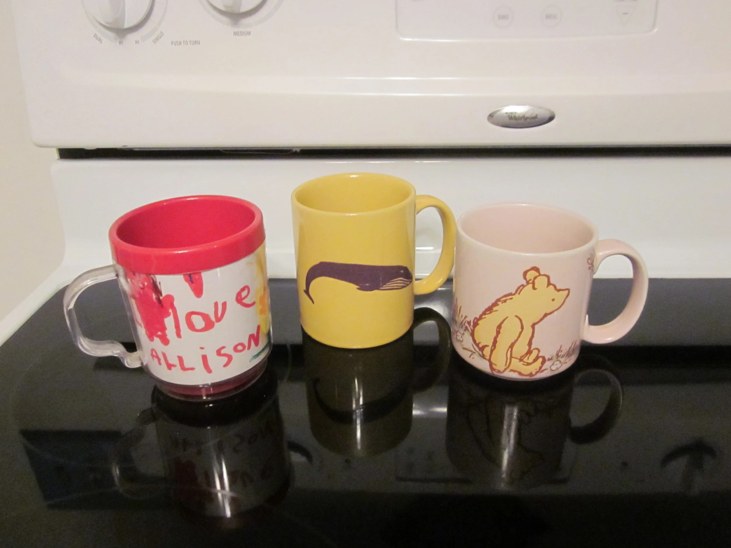 TWO SIDES TO THE STORY: PART ONE (L-R) I Love You Mom , a treasured hand-made gift from my daughter; Blue Whale changes colors when hot beverage is added to the mug, reminder of trip to my birthplace, New Bedford, MA; Winnie the Pooh on a soft pink background, comforting reminder of my daughter's childhood, my days as a bookseller in the children's department at Barnes and Noble, and my love of children's books.