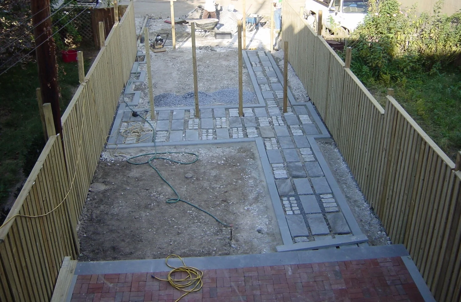 Hardscape elements of the garden begin to take shape : the new fence, the bluestone-and-granite path that leads to the driveway-to-be, and the raised brick terrace for entertaining. ©2018 Twelve gardens ltd.