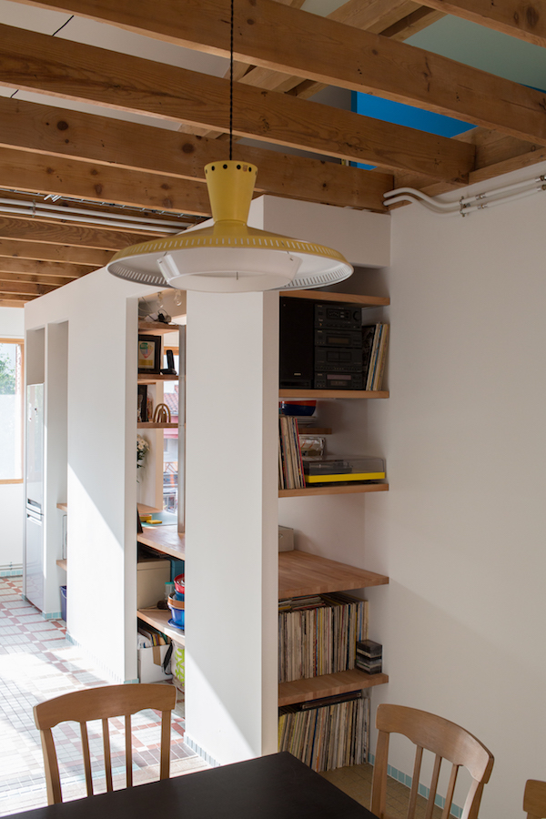  Modifier sans changer. Le projet de la maison Taquin est presque un sujet d’école. Transformer une vaste maison en deux logements pour deux couples de graphistes. Le tout avec un budget très serré. La maison d’origine, construite dans les années 50 était une maison cossue, avec des pièces aux formes génériques, de larges fenêtres, et surtout de très beaux revêtements de sol en marbre, terrazzo et grès. La géométrie des pièces ne correspondant plus au besoin des nouveaux occupants, une partie des cloisons a été découpée, et la partition a été reformulée. Les stigmates de ces transformations sont soulignées par un nouveau matériau, un carrelage bleu pâle de 5x5cm, appliqué comme une rustine soignée, témoin des relations entre ancien et nouveau, le tout dans la continuité. Dans le même soin d’économie, les cloisons d’origine étaient en brique plâtrière. Le coût des nombreuses saignées nécessaires à l’intégration des réseaux ne permettait pas d’apporter l’évolutivité nécessaire aux besoins professionnels des propriétaires. Les nouveaux réseaux d’eau, d’alimentation électriques et de chauffage sont apparents, et constituent une sorte de sculpture rampante sur les murs et plafonds. La nouvelle partition de l’espace provoque des glissements et des superpositions de fonctions. Le lavabo bleu lagon de l’ancienne salle d’eau trône au milieu de la cuisine / salon de musique / bureau. Le lave-linge buanderie communique directement sur les chambres. Le bureau et la cuisine sont séparés d’un meuble multifonction. La palette de couleur des murs, définie par les graphistes, témoigne de leur propre travail, un peu à la façon d’une carte chromatique écrite à 10 mains.
