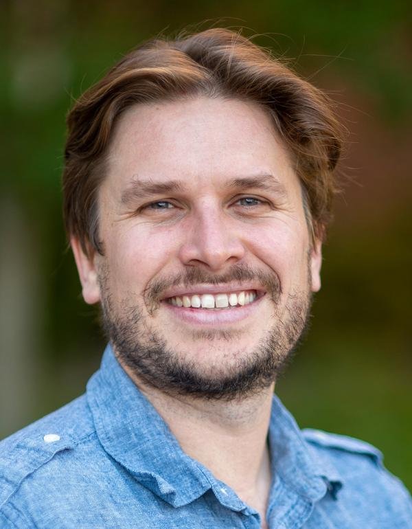 Portrait of a man with brown hair wearing a light blue shirt.