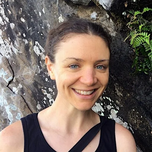 Portrait of a woman with brown hair in a black tank top.