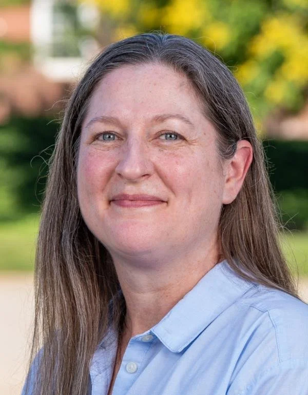 Portrait of a woman with light brown hair wearing a light blue shirt.