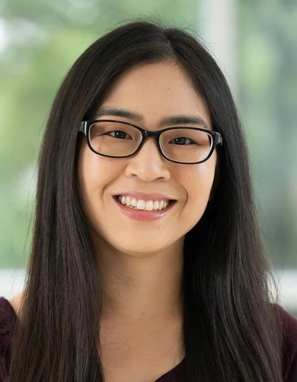 Portrait of a woman with dark hair wearing a black shirt and glasses.