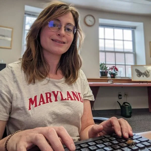 Portrait of a woman with light brown hair in a t-shirt that reads "MARYLAND."