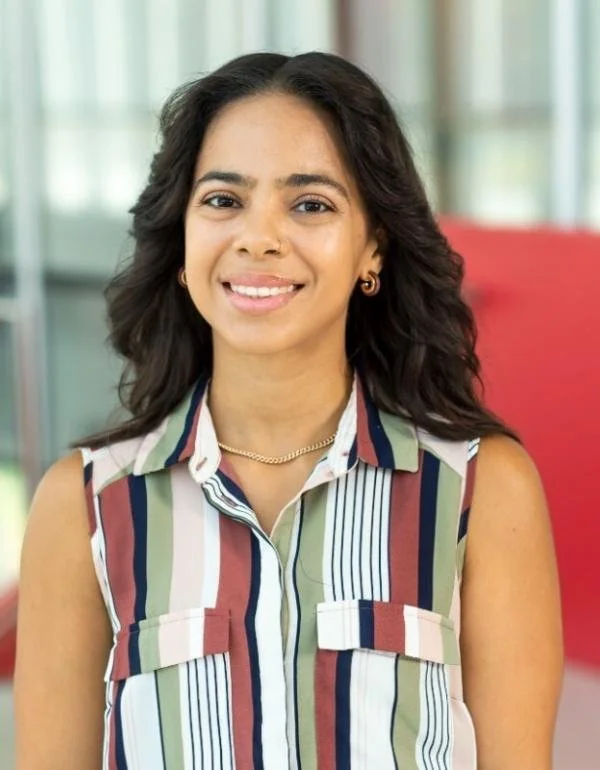 Portrait of a woman with dark brown hair wearing a stripe-patterned shirt.