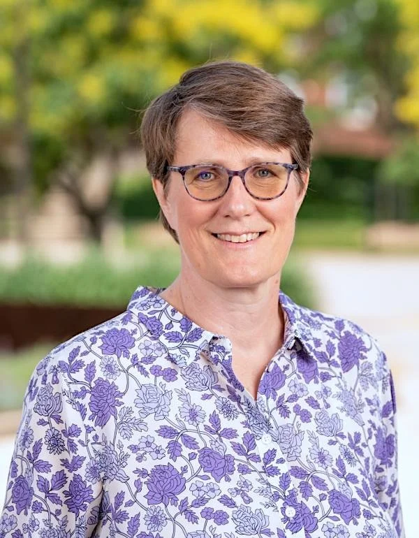 Portrait of a woman with brown hair wearing a purple shirt.