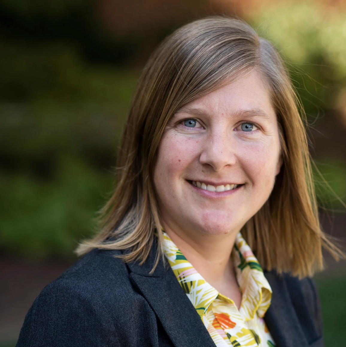 Portrait of a woman with light brown hair wearing a black blazer.