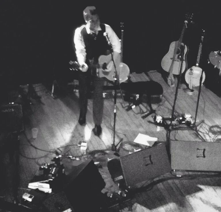 Black and white photo of Geoffrey Louis Koch performing solo at Old Rock House, taken from balcony above.