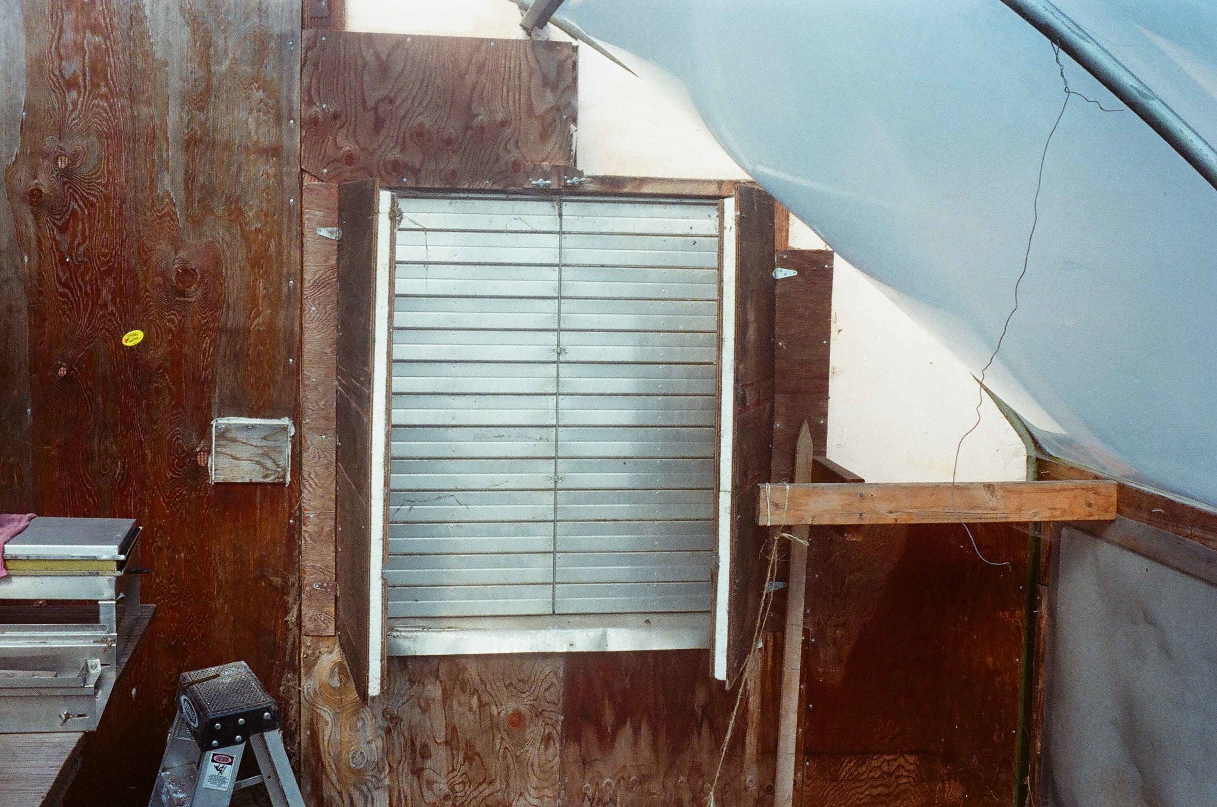  This air shutter allows fresh air into the greenhouse on warm days. The insulated doors are closed at night to prevent heat loss. The wooden end walls, surrounding the shutters, are also insulated. 
