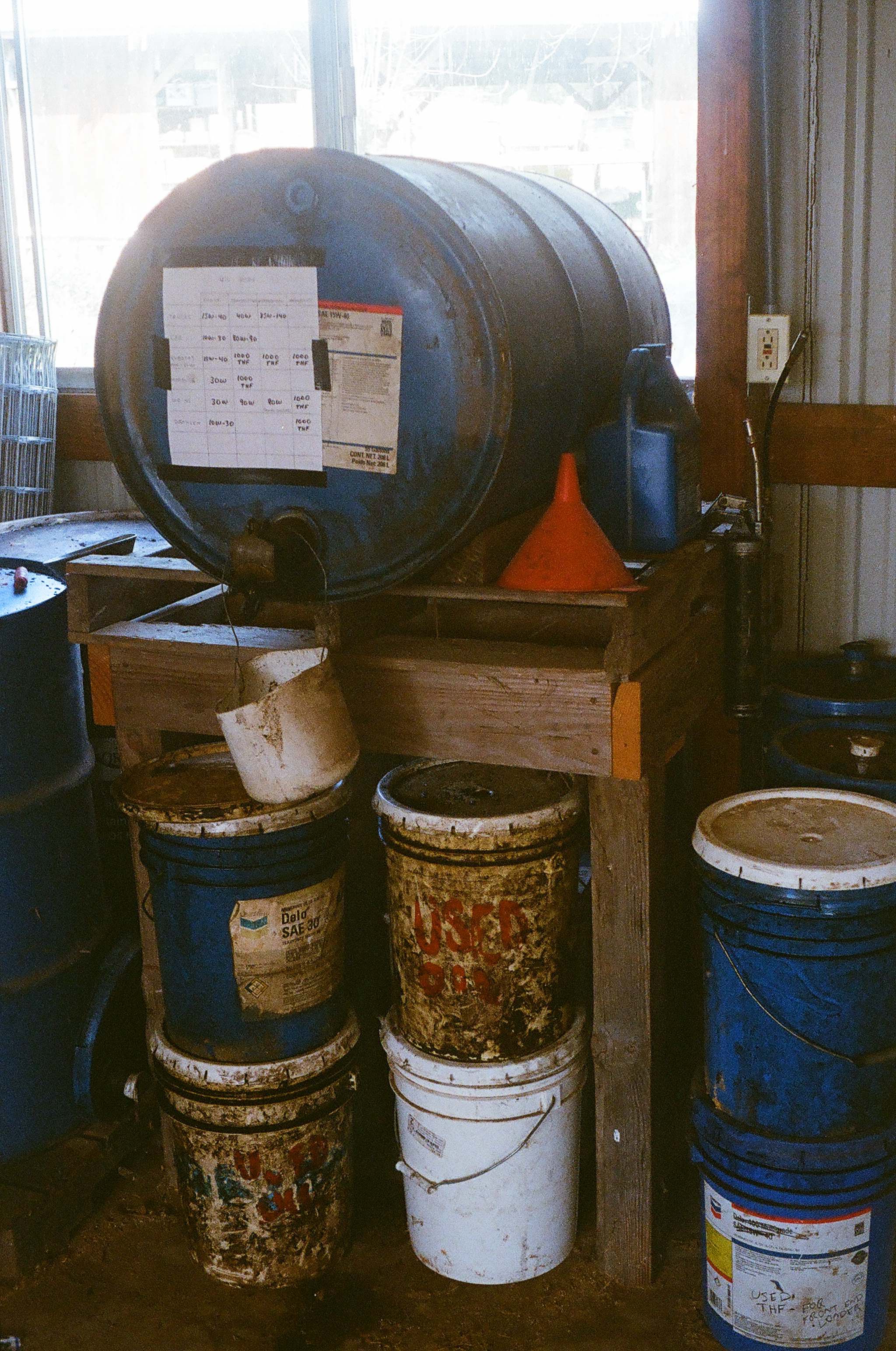Motor oil is purchased in reusable drums rather than nonrecyclable plastic containers. These buckets on the floor hold used oil that is waiting for transport to a recycling facility.