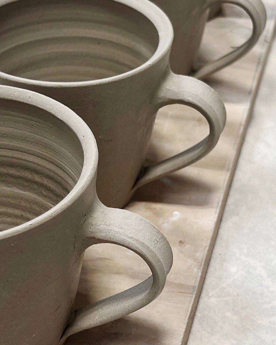 Freshly handled mugs. I've made hundreds of mugs lately for a project and continue to learn about pulling handles that have a graceful shape and avoid looking labored. 

These will dry slowy for at least a week to prevent cracking, before the first (