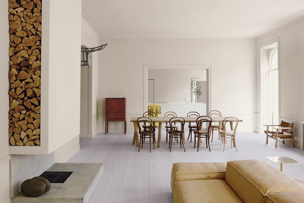 The living area is defined by a modular sofa by Piero Lissoni for Living Divani, a fireplace and a dining table conceptualized by Italian-Austrian designer Matteo Thun and manufactured by Riva 1920. The table is surrounded by antique Thonet chairs, and a chair-clock on the wall is by the Austrian artist Markus Hofer. Credit Henry Bourne