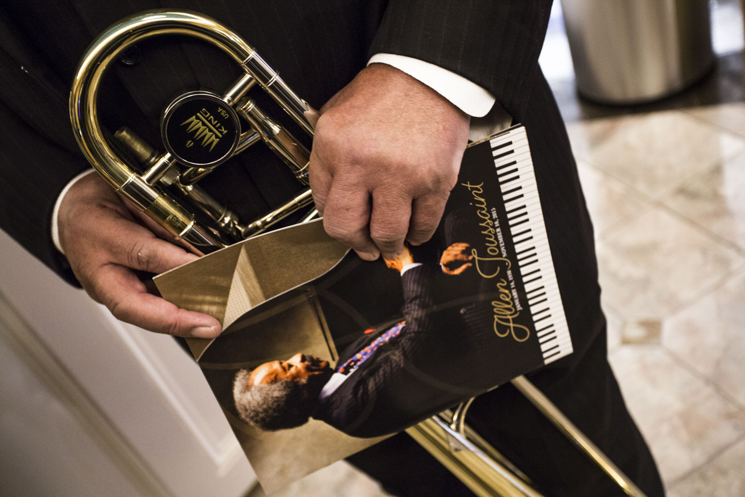 A musician holds his trombone as close as he does the Allen Toussaint memorial program book. 11/20/15 ©Zack Smith Photography