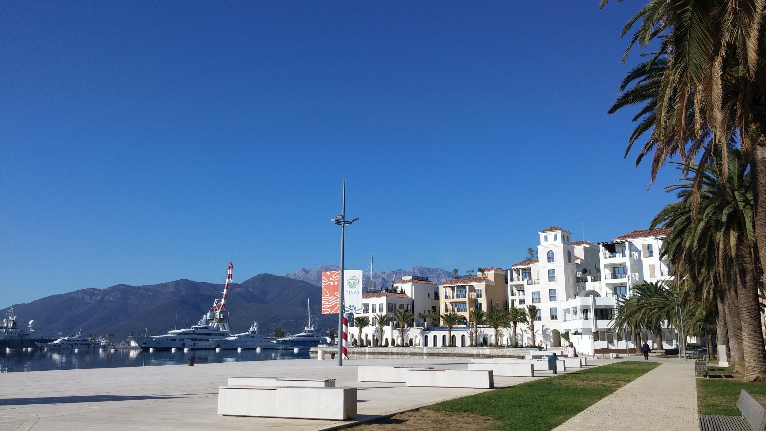 TIVAT , located in the central part of the Boka Kotorska Bay Only a 15 minutes ride from Kotor, Tivat is a cosy and pleasant place to visit. In Tivat there is a lot of interesting attractions to see, such as Renaissance Summer House Buca in the center of the city, Flower Island, or Plavi Horizonti beach. Have a cup of Espresso on Šetalište Pine and watch multi-million dollar yachts anchored in Porto Montenegro, the biggest, luxurious marina in Montenegro. If you want to cool off, take a walk through City Park and read a good book surrounded by tall trees.