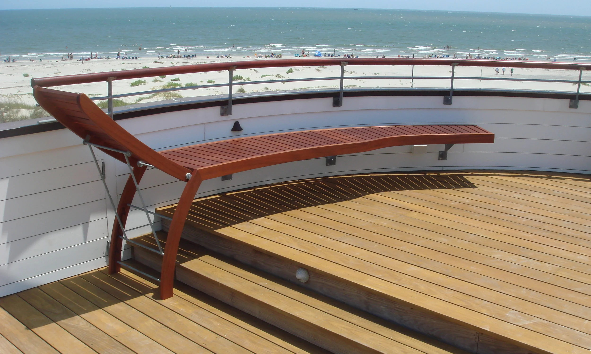  We were invited back to provide solutions for rooftop deck furnishing at a previously designed Sullivan's Island beach house. We designed Sapele chaises and a bench to integrate with the radius shape, firmly anchoring into the walls with galvanized 
