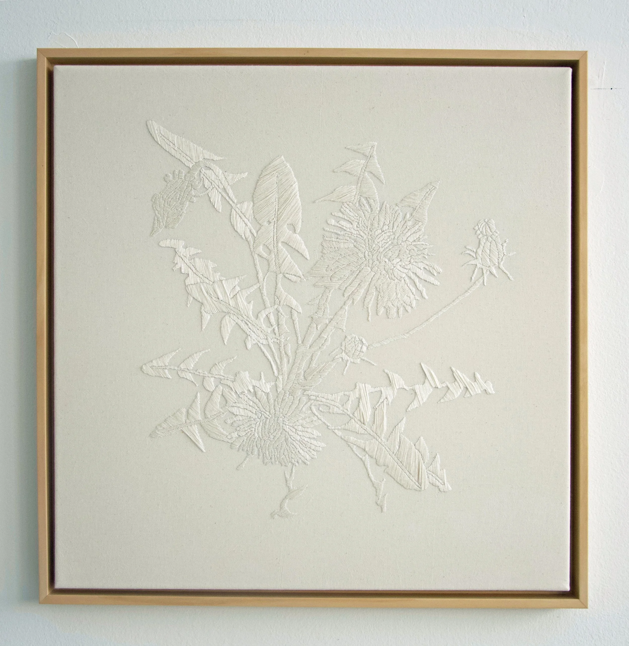 Ein weißes Wandbild mit erhabener Blumen- und Blatt-Embossing im Rahmen.