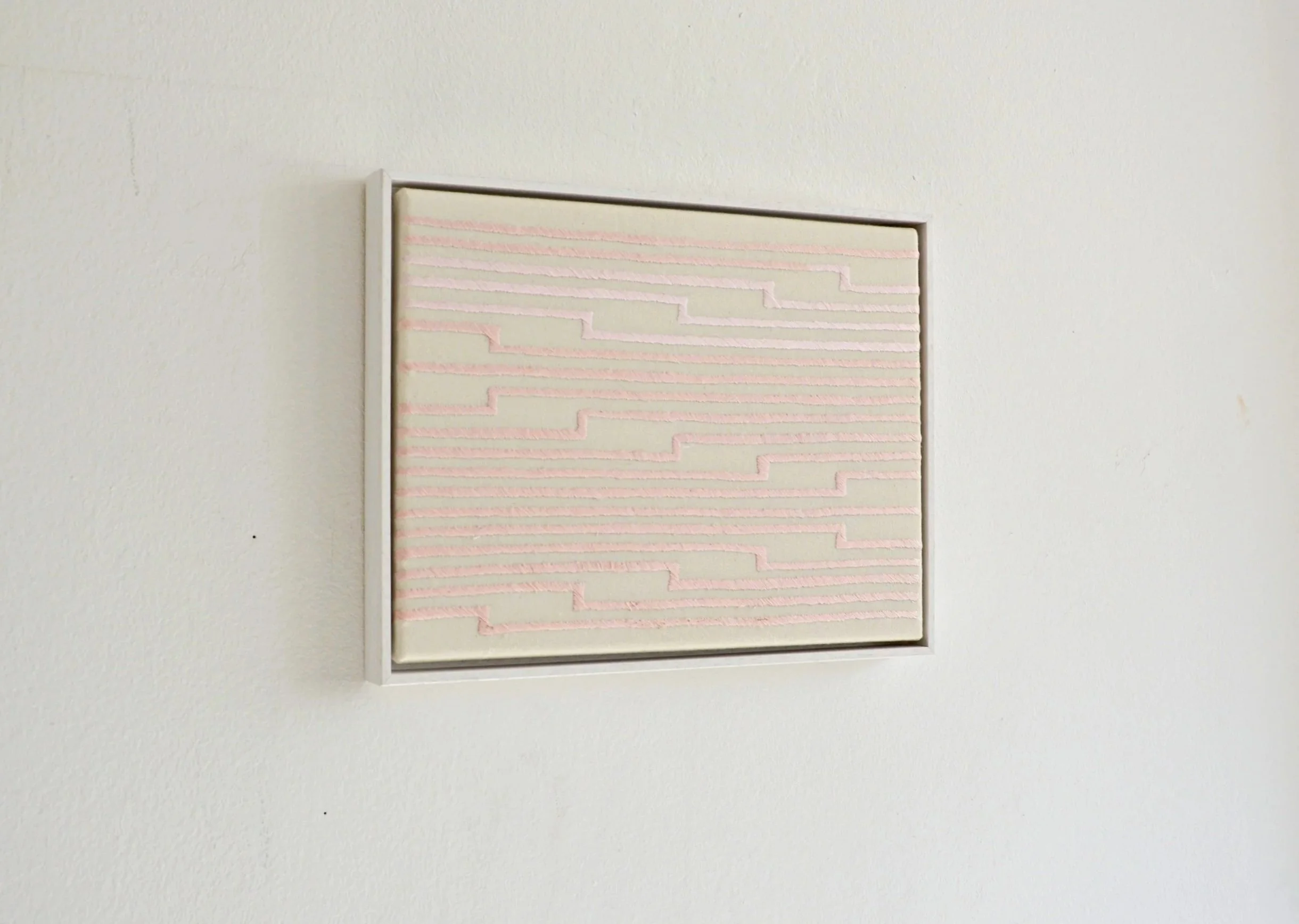 Abstraktes Kunstwerk mit pinken, erhabenen Linien auf einer weißen Wand.