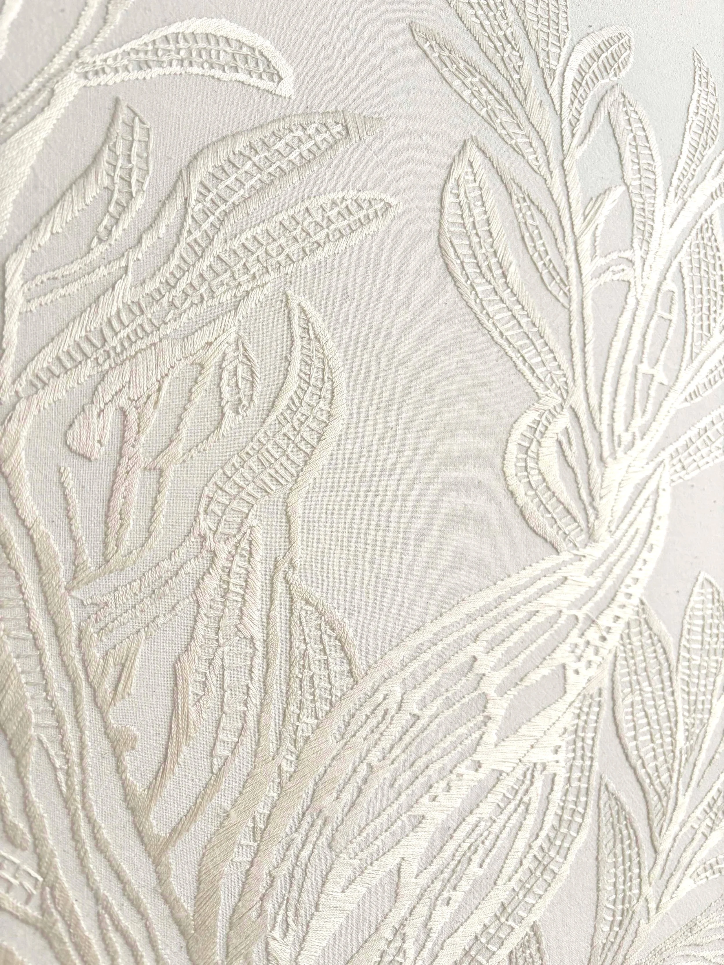 Nahtlose weiße Stickerei mit Blatt- und Astmustern auf Stoff