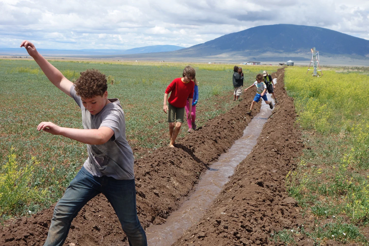 Summer campers from Sangre de Cristo Youth Ranch jump with joy at the first flood flow on Costilla Farm