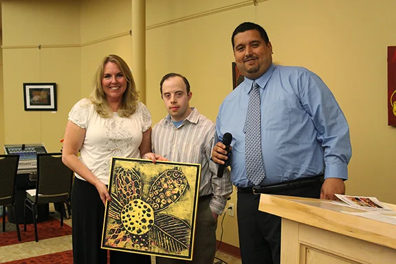 Self-Advocacy Committee President Victor Colon (far right) presents Joan Volpe with a painting by Artist Ross Carangelo,