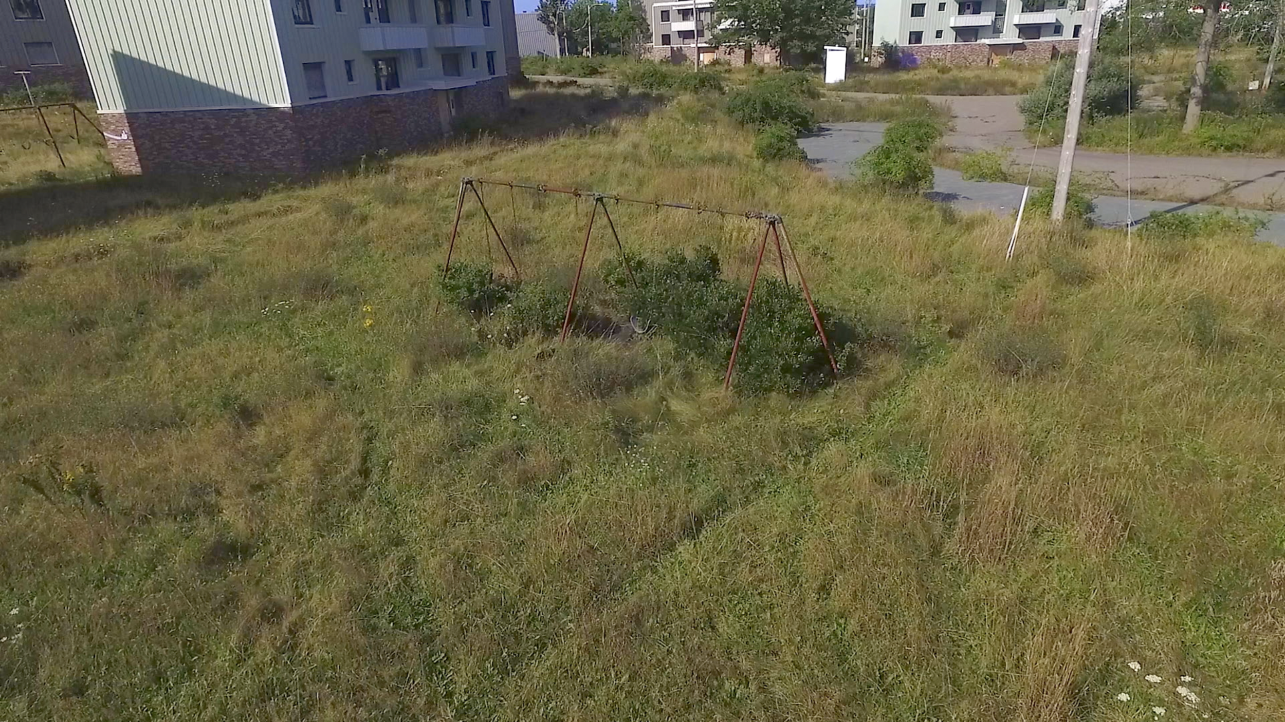 A swing set rusting away in the decay, a community filled with children at one time.