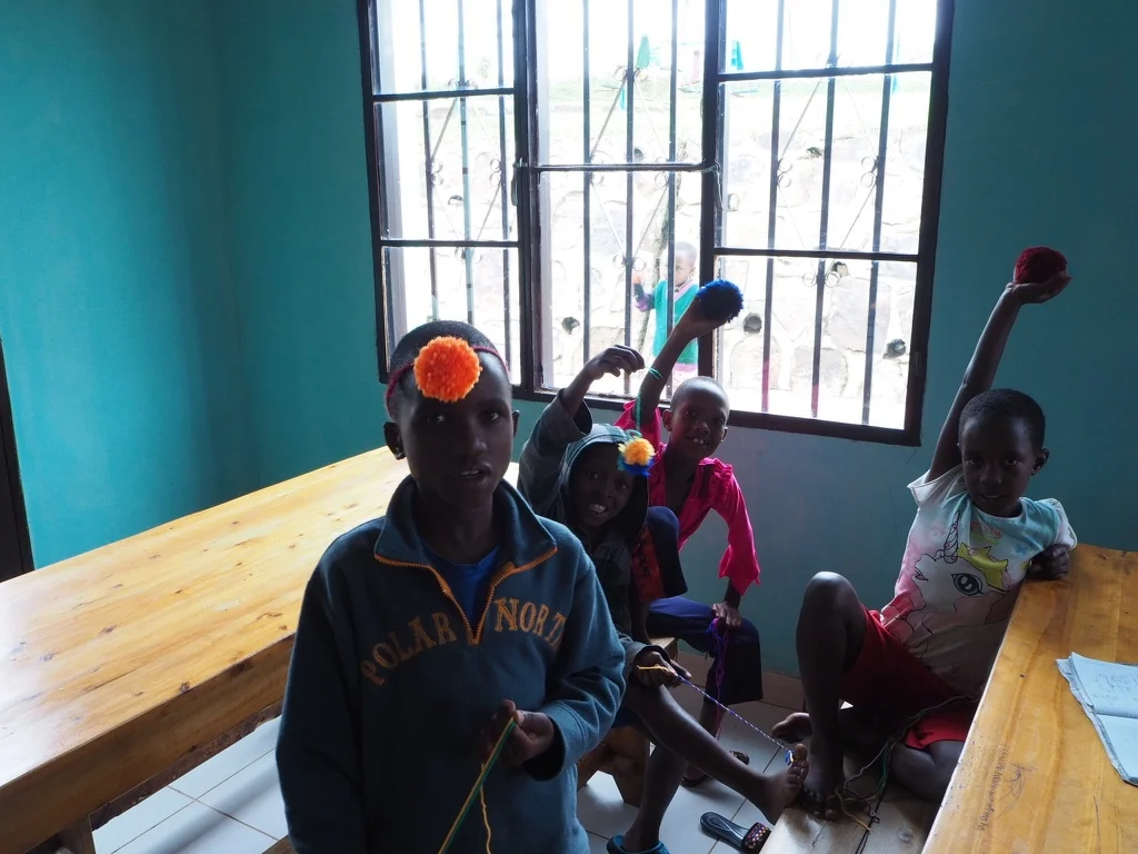 Little Claude, Agide, Levine and Sarah proudly showing off their pom poms. I'd heard that the kids don't get to do much in the way of arts and crafts and seeing as wool is so light in weight I could take an abundance over and teach them how to make pom poms...