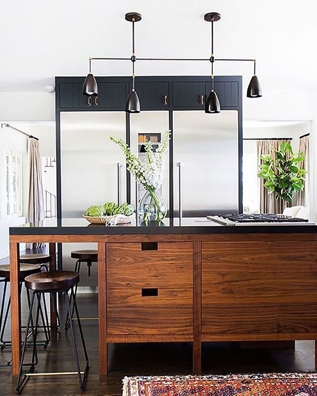 &bull; A simple variation in color and texture between a kitchen island and kitchen cabinets adds so much interest and dimension to a space. This welcoming kitchen features a wooden island with deep brown cabinets that stand out against the black cou