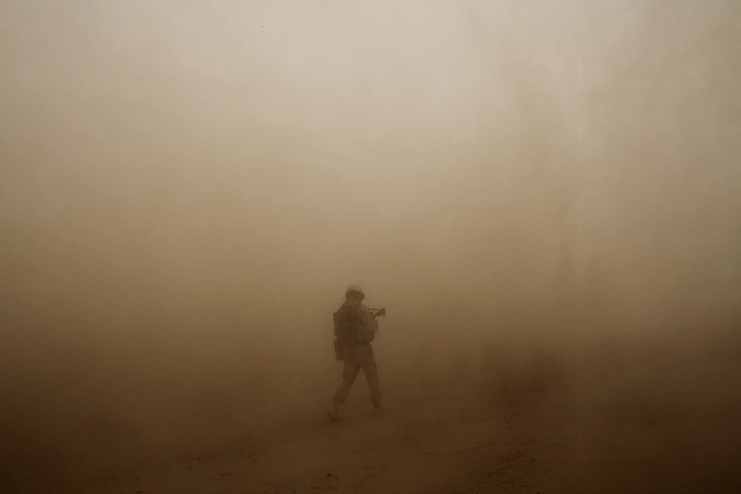 A U.S. Marine walks in the dusty rotor wash of a helicopter in Marja District, Helmand Province, Afghanistan.