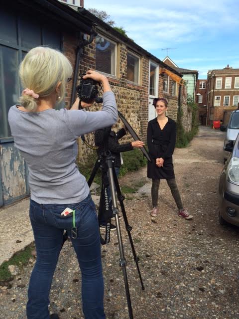 The light is filtering through the clouds and Sarah Lomax is kindly and skillfully holding the reflector up to the shadow side of model Hasia's face. Photo by Rachel Skinner