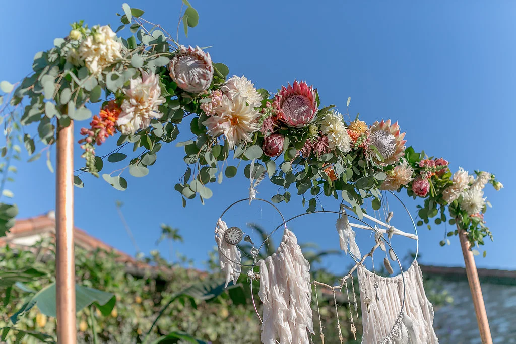 Desert bohemian wedding ceremony with copper arch and floral garland by Compass Floral | Estancia Hotel & Spa, La Jolla.