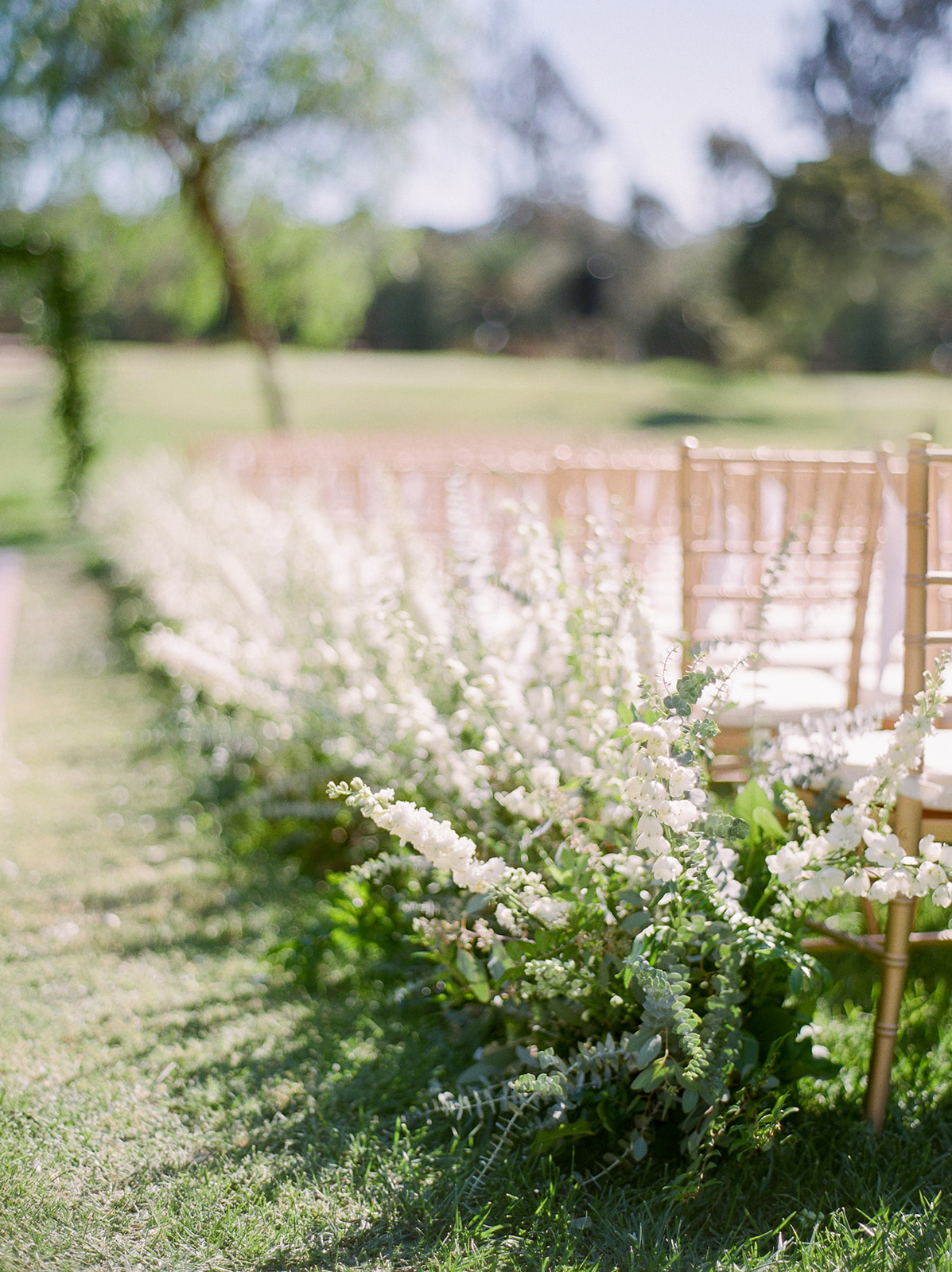 Outdoor wedding ceremony aisle lined with flowers | Rancho Santa Fe Golf Club | Compass Floral | Wedding Florist in San Diego and Southern California | Rachael McCall Photography