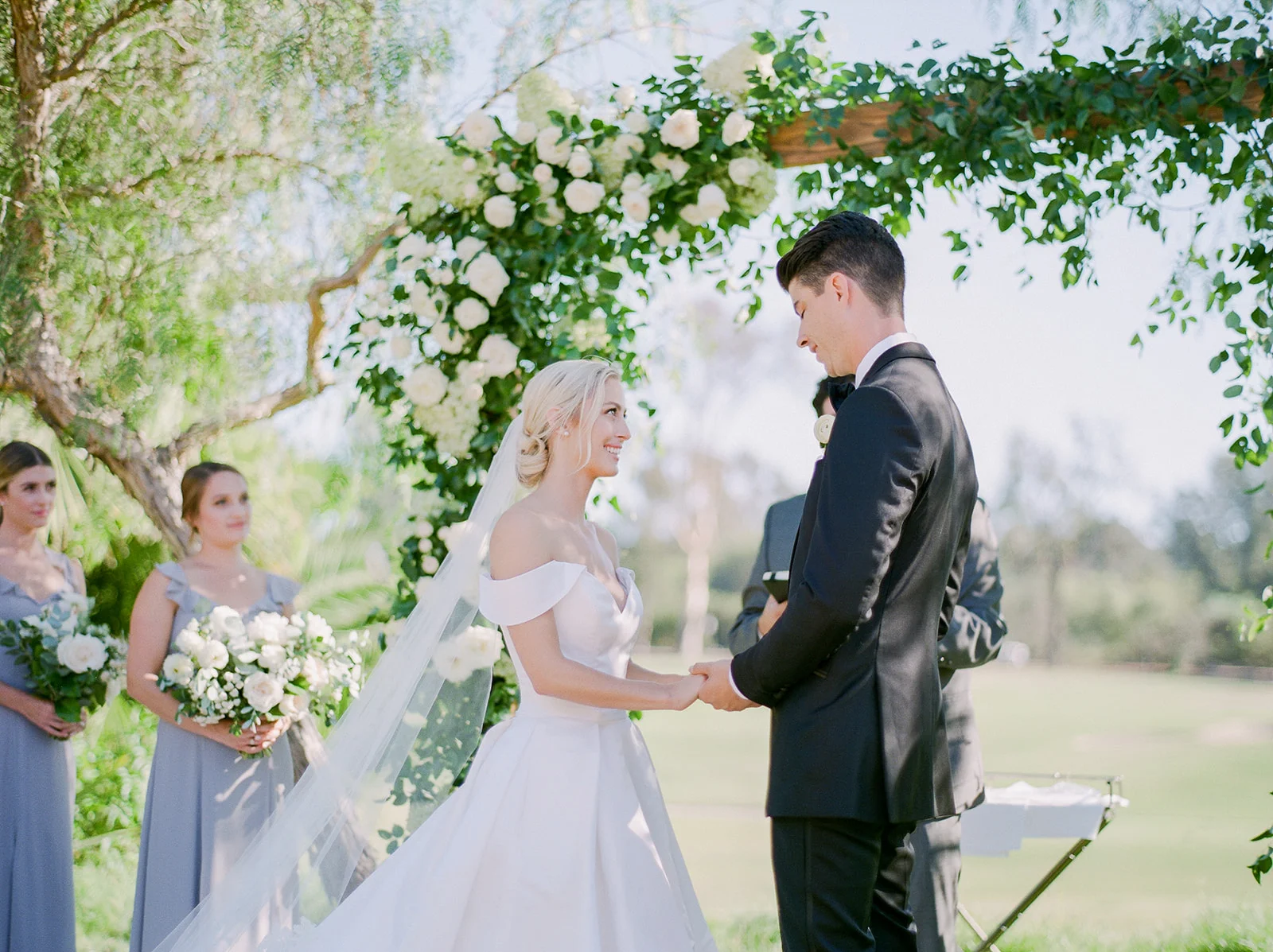 Bride and groom under greenery & white flower covered arch | Rancho Santa Fe Golf Club | Compass Floral | Wedding Florist in San Diego and Southern California | Rachael McCall Photography