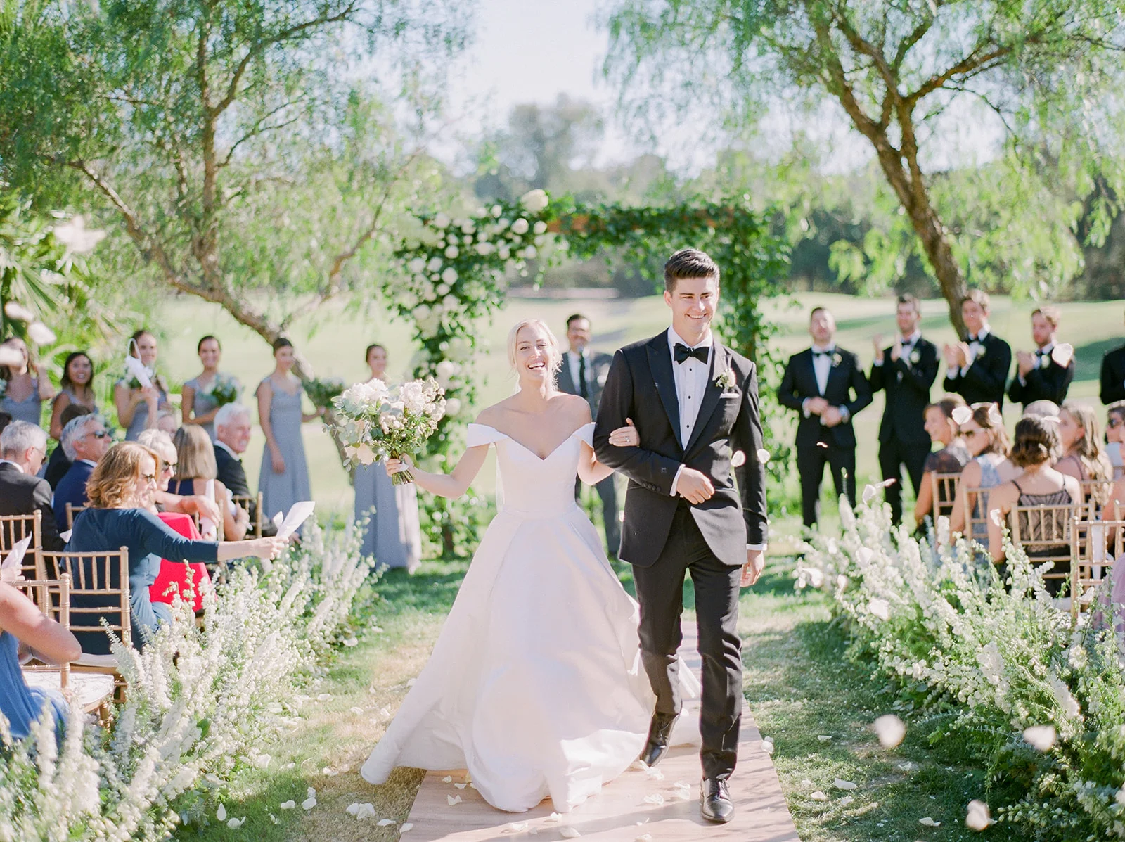 Bride and groom walk down flower lined aisle | Rancho Santa Fe Golf Club | Compass Floral | Wedding Florist in San Diego and Southern California | Rachael McCall Photography