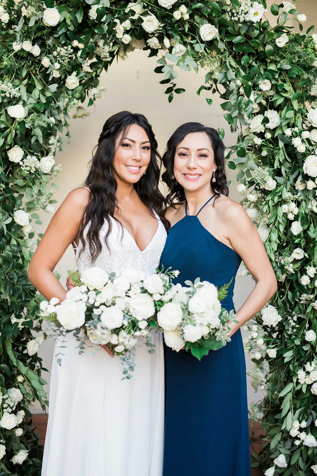 Bride and bridesmaid with white bouquets under greenery arch | Darlington House, La Jolla | Compass Floral | Wedding Florist in San Diego and Southern California | My Sun and Stars Co. Photography