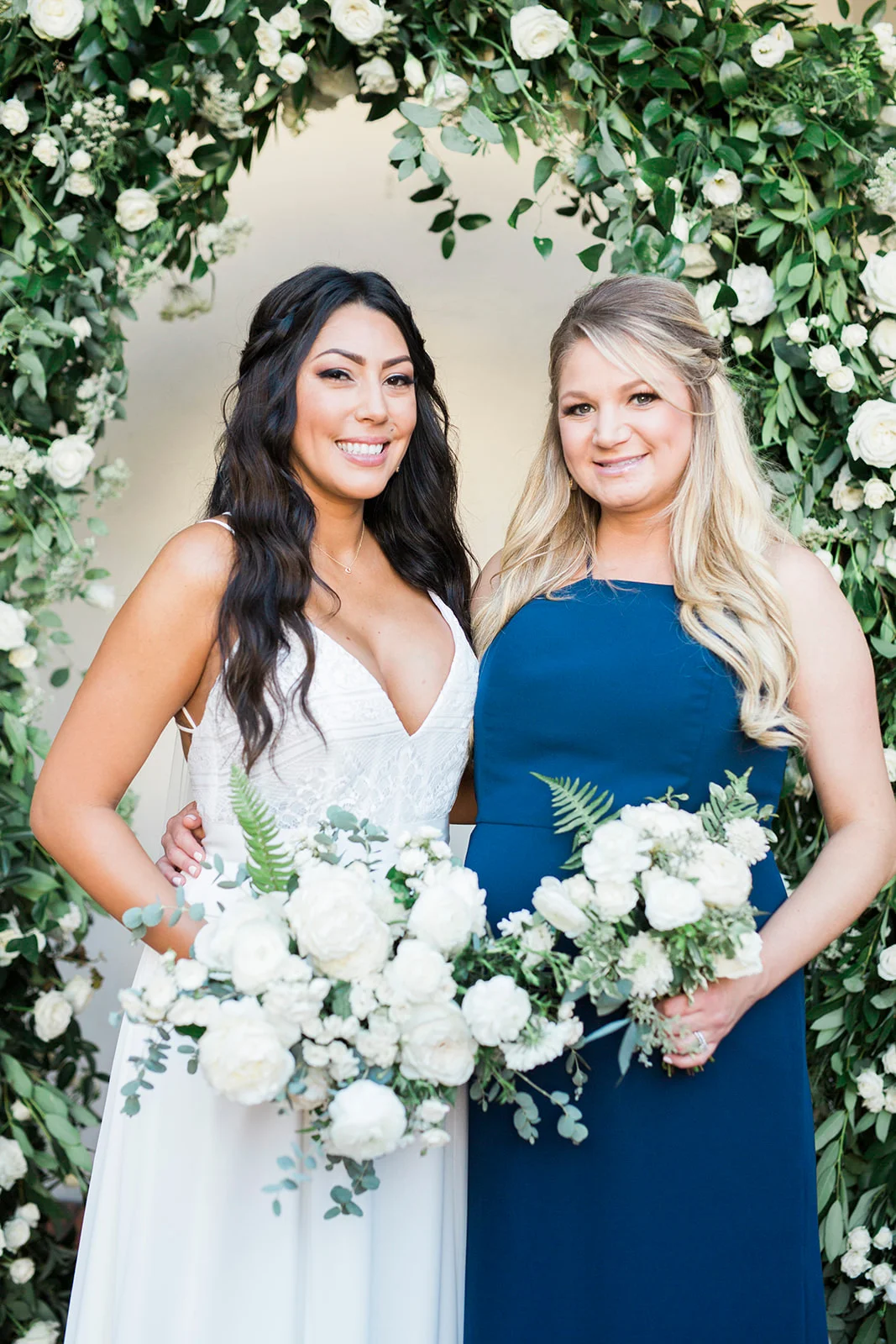 Bride and bridesmaid with white bouquets under greenery arch | Darlington House, La Jolla | Compass Floral | Wedding Florist in San Diego and Southern California | My Sun and Stars Co. Photography