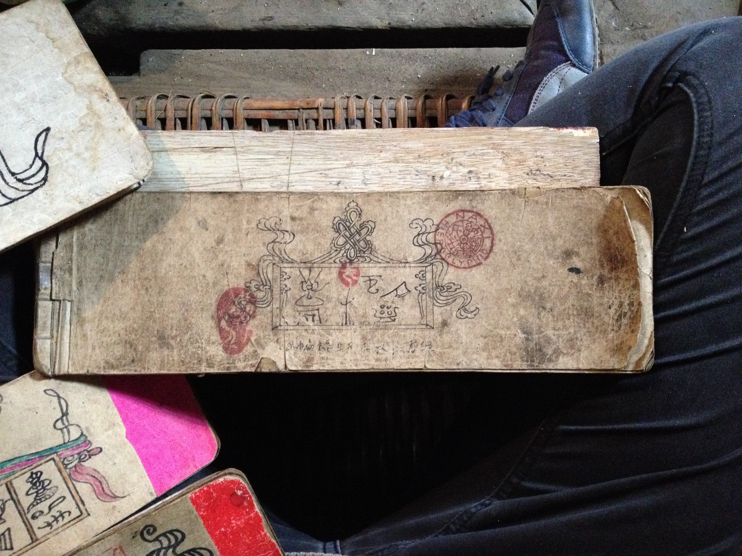 Thumbing through a selection of He Xiudong's Dongba scriptures in Tacheng. Featured above is a book drawn by his grandfather...
