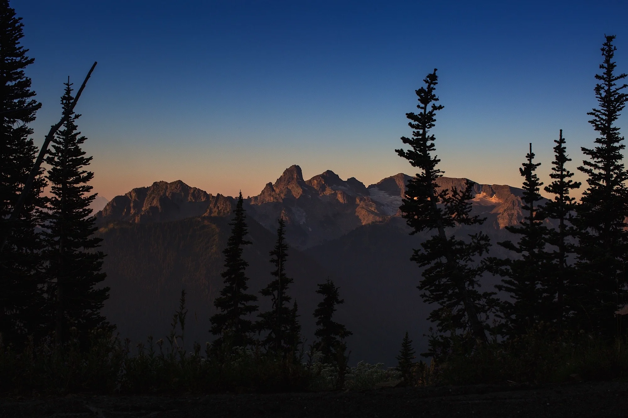 sunrise over the peaks surrounding mt. rainier