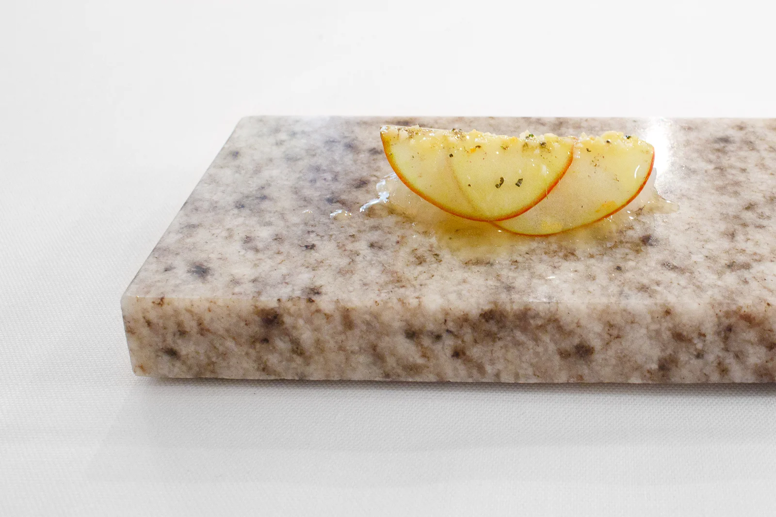 Amuse Bouche: Roughly chopped raw langoustine from Ingemar Johansson under autumn apple shavings, rosemary, and almonds.