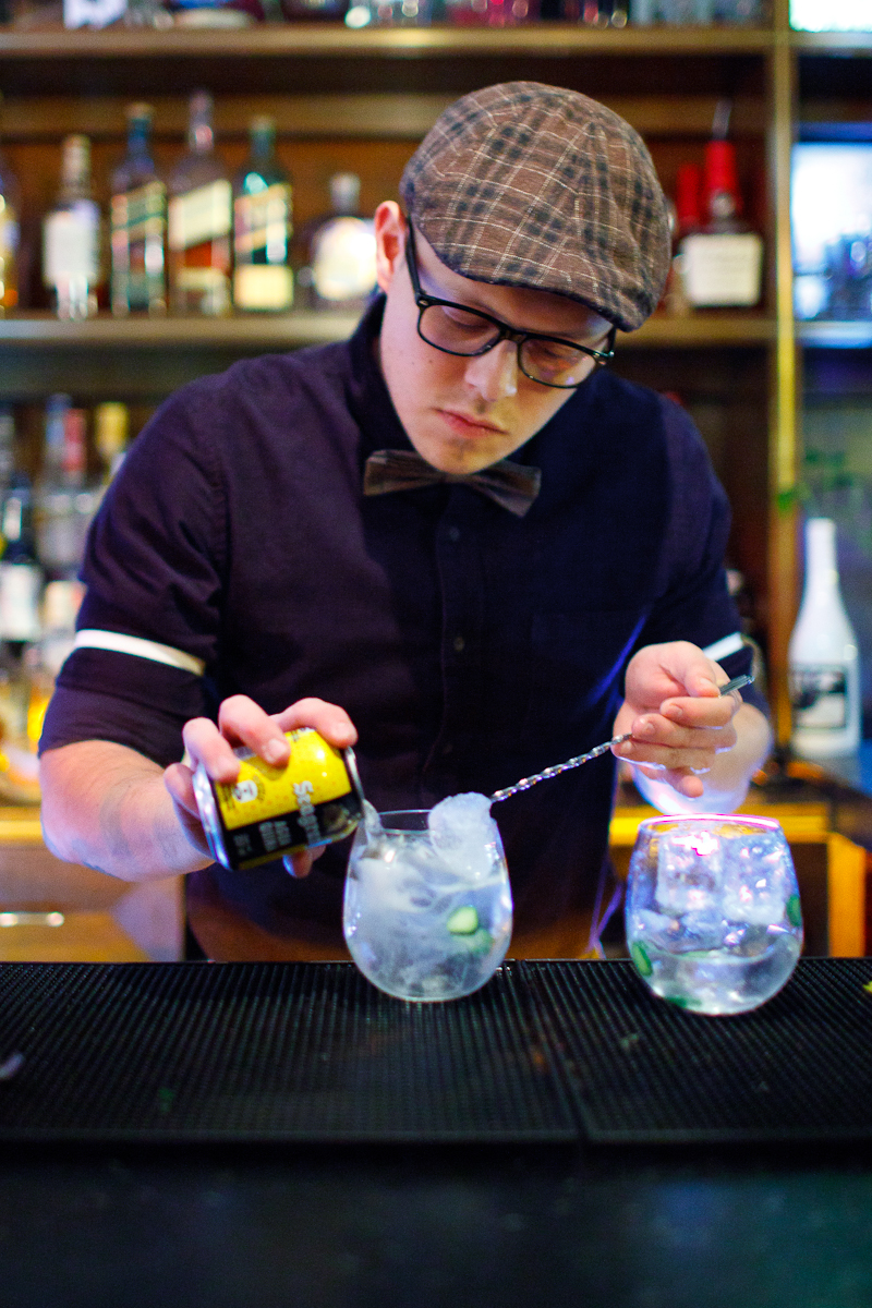 Making a Gin & Tonic. Pouring tonic water over a spoon to balance the carbonation.