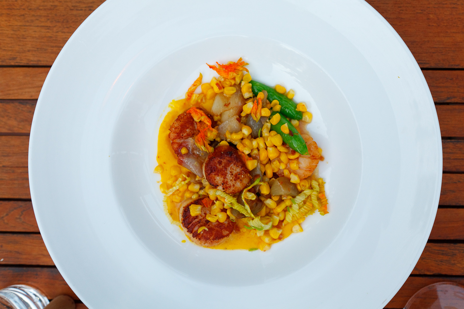 Pan seared scallops, saffron-corn puree, snap peas, corn shallots, squash blossom, bacon vinaigrette ($26)